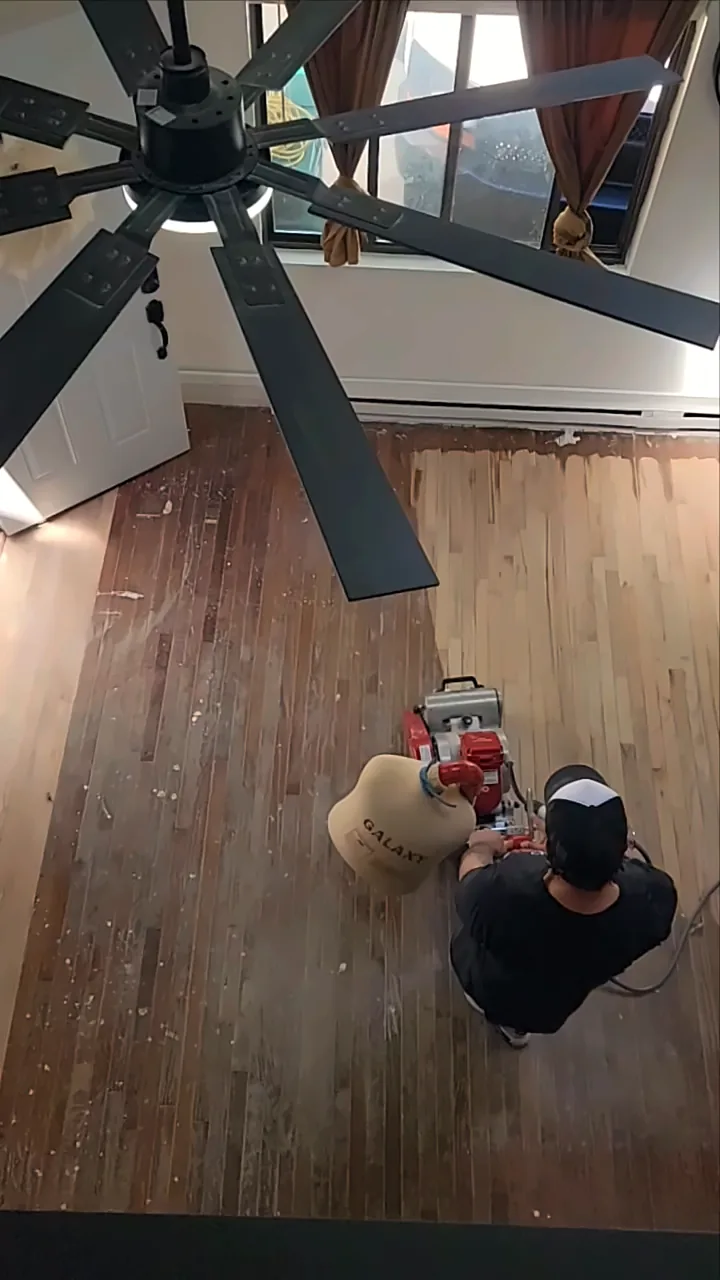 Overhead view of a floor being sanded, fresh wood next to the old finish