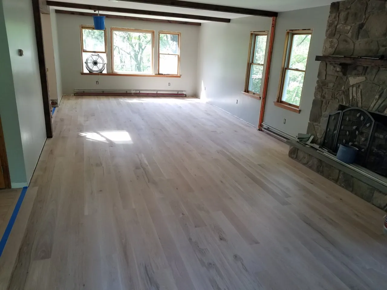 New white oak floor in a great room with a stone fireplace
